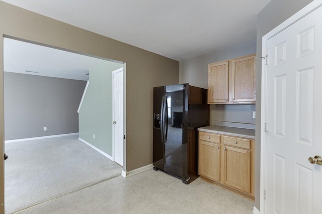 kitchen featuring light carpet, black fridge with ice dispenser, baseboards, light countertops, and light brown cabinetry