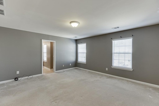 unfurnished room with visible vents, baseboards, and light colored carpet