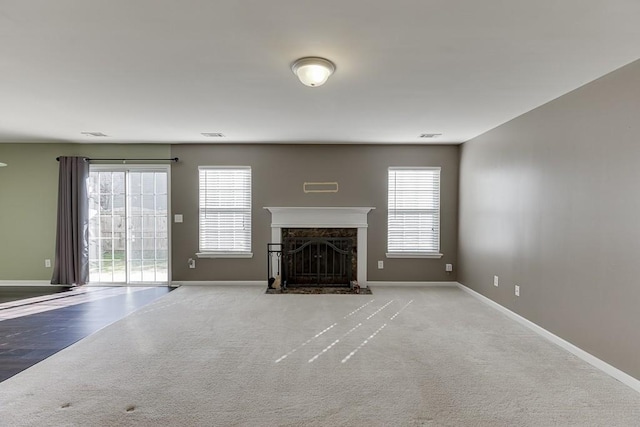 unfurnished living room with carpet floors, a high end fireplace, and baseboards