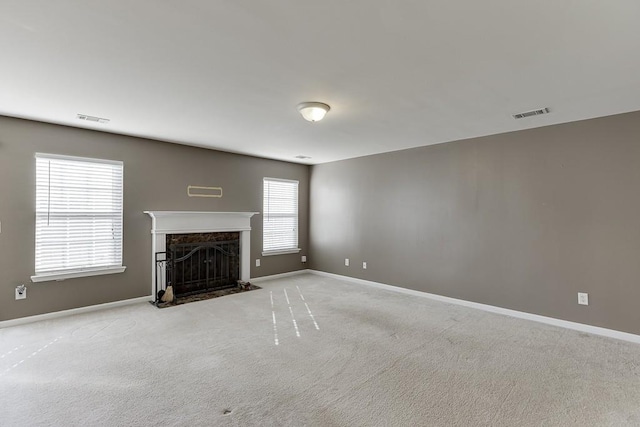 unfurnished living room with baseboards, a premium fireplace, visible vents, and carpet flooring