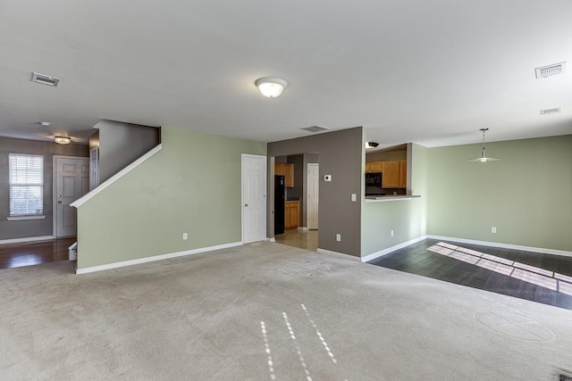 unfurnished living room featuring carpet flooring, visible vents, stairway, and baseboards