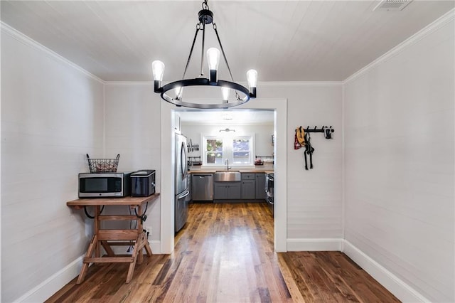 dining area featuring crown molding, a chandelier, hardwood / wood-style flooring, and sink