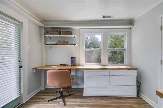 home office featuring ornamental molding, built in desk, and light hardwood / wood-style floors