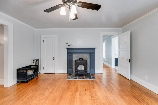 living room featuring a wood stove, hardwood / wood-style flooring, ceiling fan, and ornamental molding