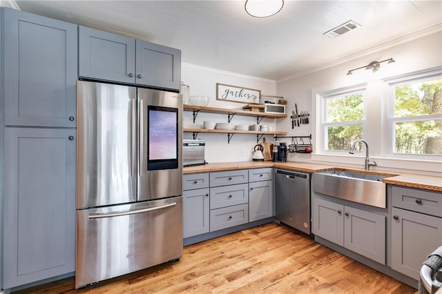 kitchen featuring light wood-type flooring, sink, crown molding, appliances with stainless steel finishes, and gray cabinets