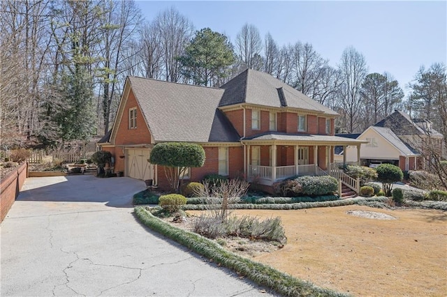 view of front of house featuring covered porch, brick siding, a garage, and aphalt driveway