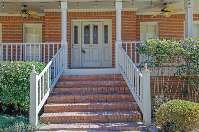 doorway to property with covered porch, ceiling fan, and brick siding