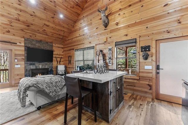 kitchen with light countertops, wood walls, dark brown cabinets, light wood-type flooring, and a lit fireplace