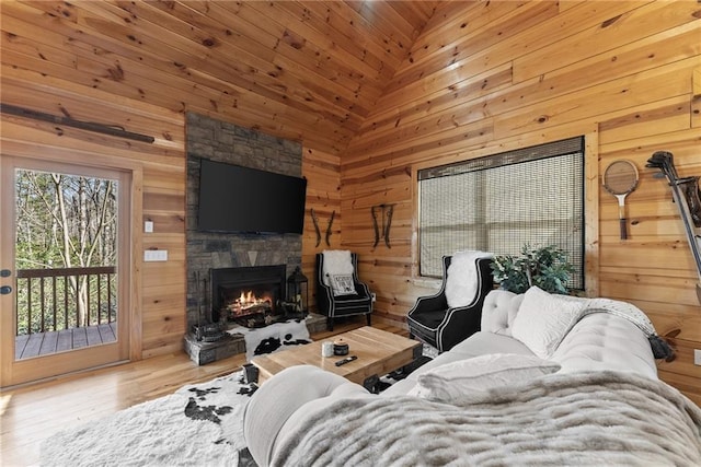 living room featuring wooden walls, high vaulted ceiling, a fireplace, and wood finished floors