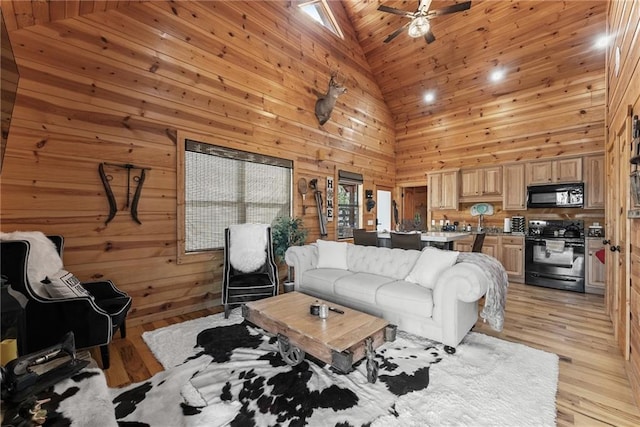 living room featuring ceiling fan, high vaulted ceiling, light wood finished floors, and wooden walls