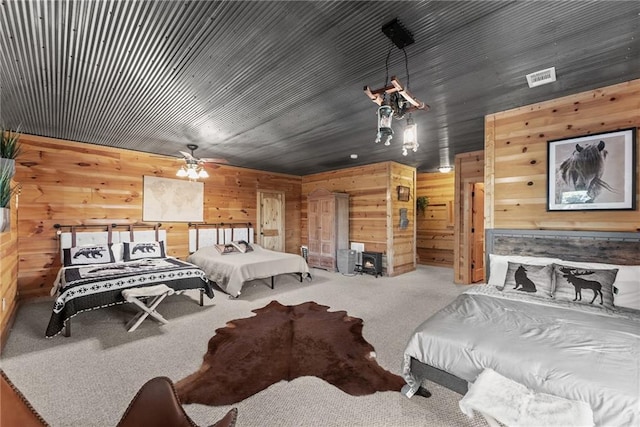 carpeted bedroom featuring visible vents and wood walls