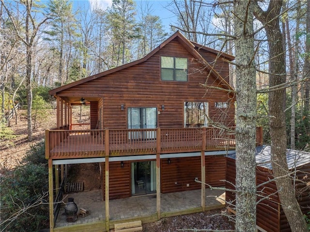 rear view of property with a deck, a patio area, a ceiling fan, and faux log siding