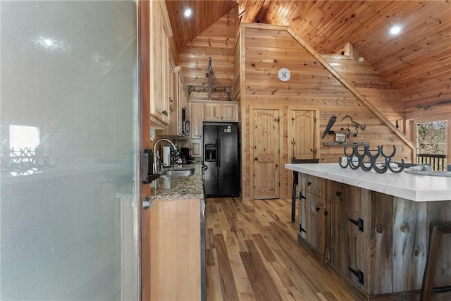 kitchen featuring light wood finished floors, lofted ceiling, a sink, wooden ceiling, and black fridge