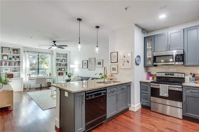 kitchen featuring ceiling fan, sink, dark hardwood / wood-style flooring, kitchen peninsula, and appliances with stainless steel finishes