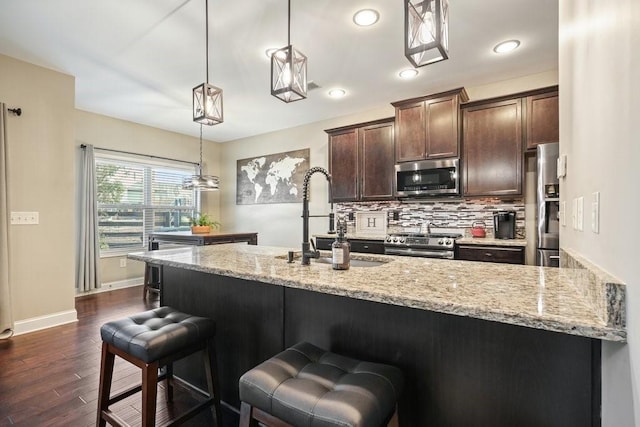 48 Ironwood Ct, Dallas, GA 30132 - kitchen featuring dark brown cabinetry, a sink, appliances with stainless steel finishes, backsplash, and light stone countertops