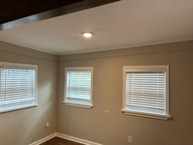 empty room with crown molding, plenty of natural light, and dark hardwood / wood-style flooring