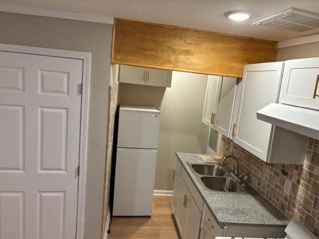 kitchen featuring white cabinetry, sink, backsplash, white fridge, and light stone countertops