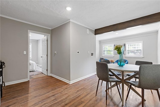 dining space with crown molding, wood-type flooring, beam ceiling, and a textured ceiling