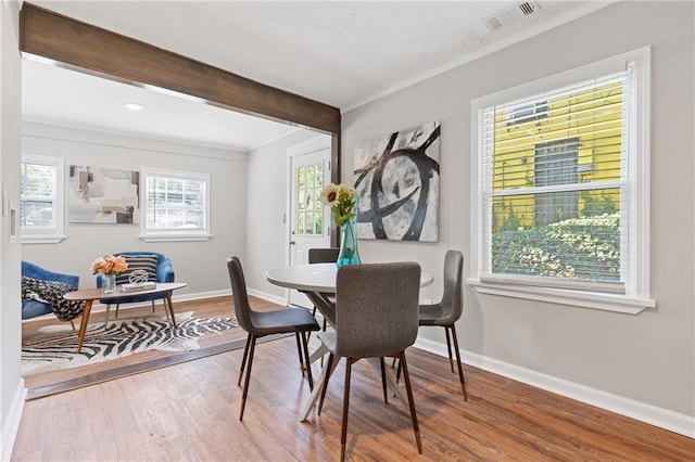 dining space with ornamental molding, hardwood / wood-style floors, and beam ceiling