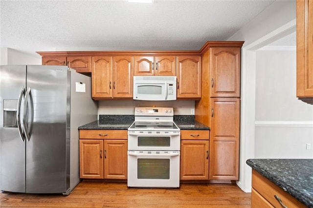 180 Butterfield Ln, Fayetteville, GA 30214 - kitchen with white appliances, light wood finished floors, dark stone countertops, brown cabinetry, and a textured ceiling