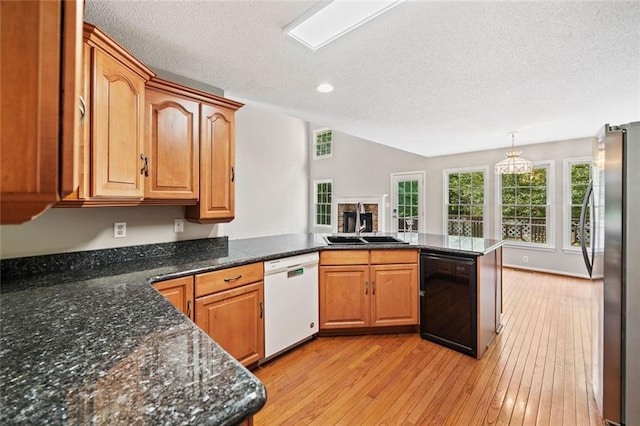 180 Butterfield Ln, Fayetteville, GA 30214 - kitchen with white dishwasher, a peninsula, a textured ceiling, freestanding refrigerator, and light wood-type flooring