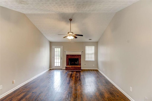 unfurnished living room featuring vaulted ceiling, a brick fireplace, ceiling fan, and dark wood-type flooring