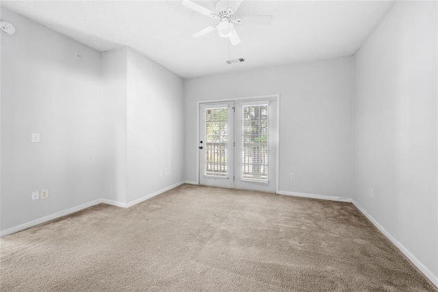 carpeted empty room featuring visible vents, a ceiling fan, and baseboards