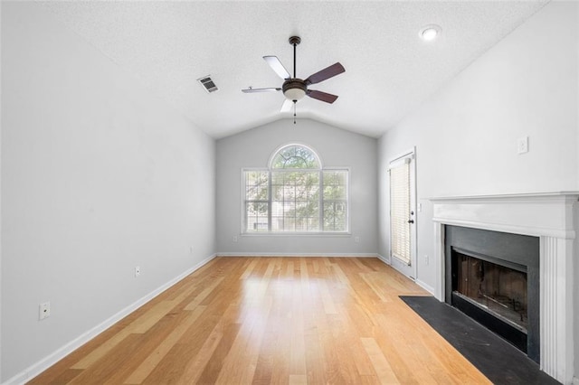 unfurnished living room featuring light wood-style floors, a ceiling fan, a fireplace with flush hearth, vaulted ceiling, and visible vents
