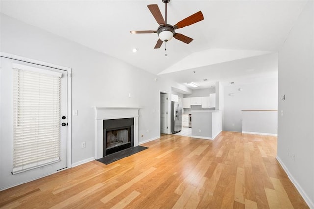 unfurnished living room with ceiling fan, a fireplace with flush hearth, baseboards, light wood finished floors, and lofted ceiling