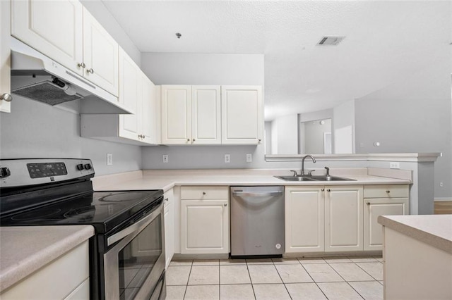 kitchen featuring visible vents, light countertops, under cabinet range hood, a sink, and appliances with stainless steel finishes