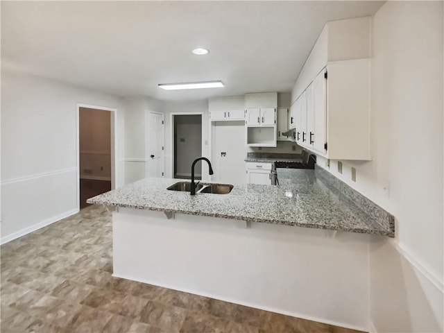 kitchen featuring white cabinets, kitchen peninsula, sink, and stove