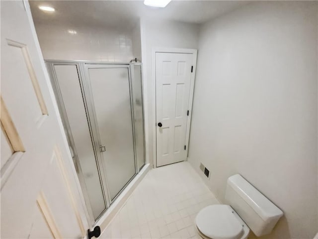 bathroom featuring toilet and a shower with door