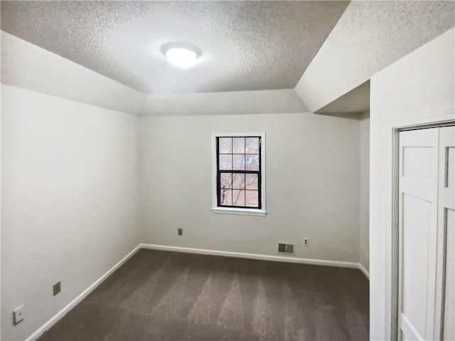 spare room with a textured ceiling and dark colored carpet