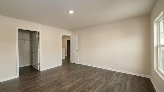 unfurnished bedroom featuring a walk in closet, dark hardwood / wood-style floors, and a closet