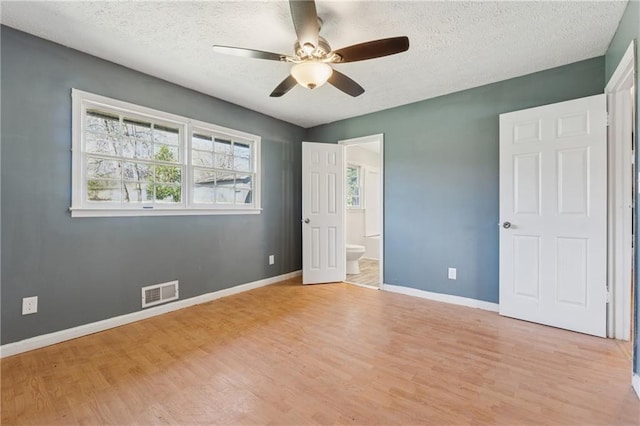 unfurnished bedroom with light wood-type flooring, visible vents, a textured ceiling, and baseboards