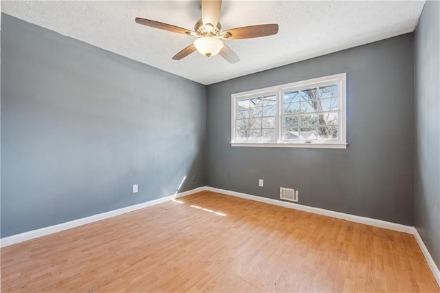 unfurnished room with a textured ceiling, visible vents, baseboards, a ceiling fan, and light wood-style floors