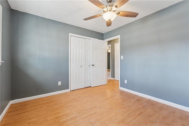 unfurnished bedroom with light wood finished floors, a ceiling fan, baseboards, and a closet