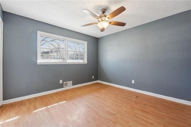 unfurnished room with wood finished floors, visible vents, and baseboards