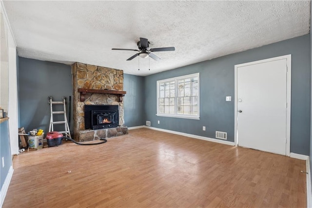 unfurnished living room featuring a textured ceiling, a fireplace, wood finished floors, and visible vents