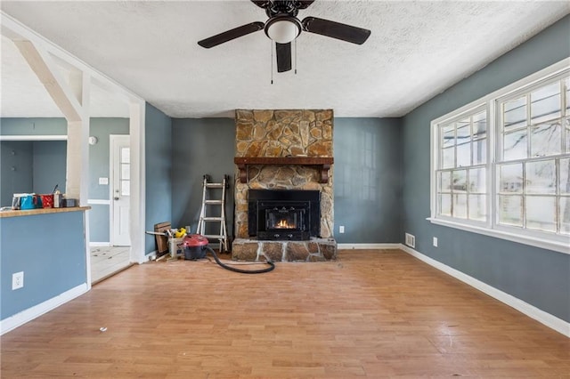 living area with a textured ceiling, a fireplace, wood finished floors, and baseboards