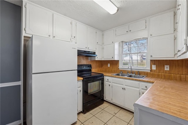 kitchen with light tile patterned floors, black range with electric cooktop, under cabinet range hood, a sink, and freestanding refrigerator