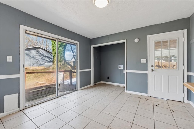 interior space with light tile patterned floors, baseboards, and a textured ceiling