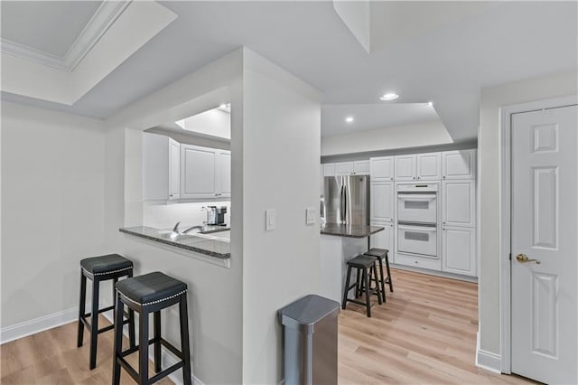 3636 Habersham Rd NW Unit 2101, Atlanta, GA 30305 - kitchen with a breakfast bar, freestanding refrigerator, double oven, a tray ceiling, and white cabinets