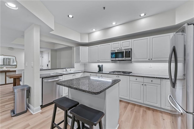 3636 Habersham Rd NW Unit 2101, Atlanta, GA 30305 - kitchen featuring stainless steel appliances, light wood finished floors, a kitchen island, a breakfast bar area, and white cabinetry