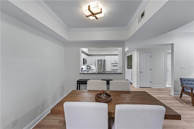 3636 Habersham Rd NW Unit 2101, Atlanta, GA 30305 - dining space featuring light wood-style flooring, ornamental molding, and a tray ceiling