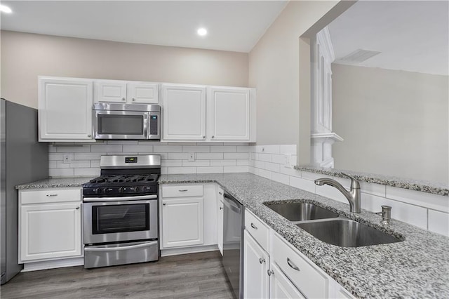 kitchen with decorative backsplash, stainless steel appliances, sink, white cabinetry, and dark hardwood / wood-style flooring