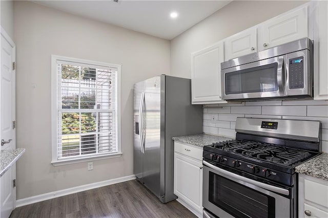 kitchen with appliances with stainless steel finishes, light stone counters, and white cabinets