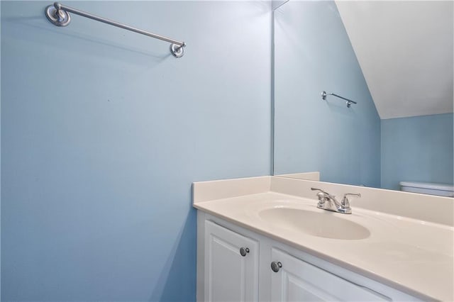 bathroom featuring vanity, vaulted ceiling, and toilet