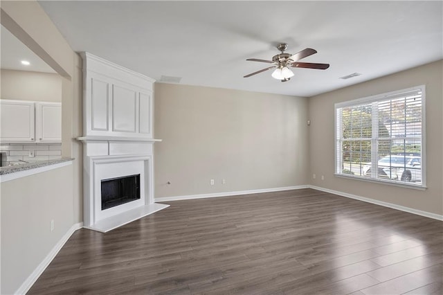 unfurnished living room featuring dark wood-type flooring, a large fireplace, and ceiling fan