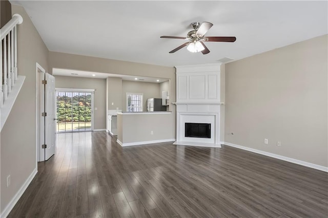 unfurnished living room with ceiling fan, a large fireplace, and dark hardwood / wood-style flooring